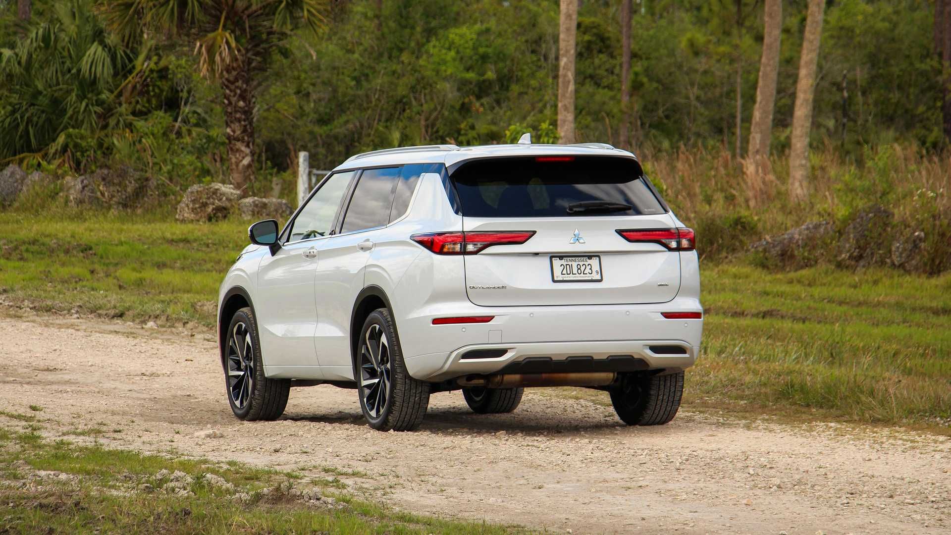 نمای عقب شاسی بلند میتسوبیشی اوتلندر / Mitsubishi Outlander سفید رنگ در جاده جنگلی