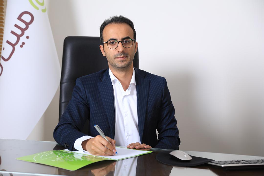 حسین طهرانی مدیرعامل مبین نت در دفتر با پرچم مبین نت
