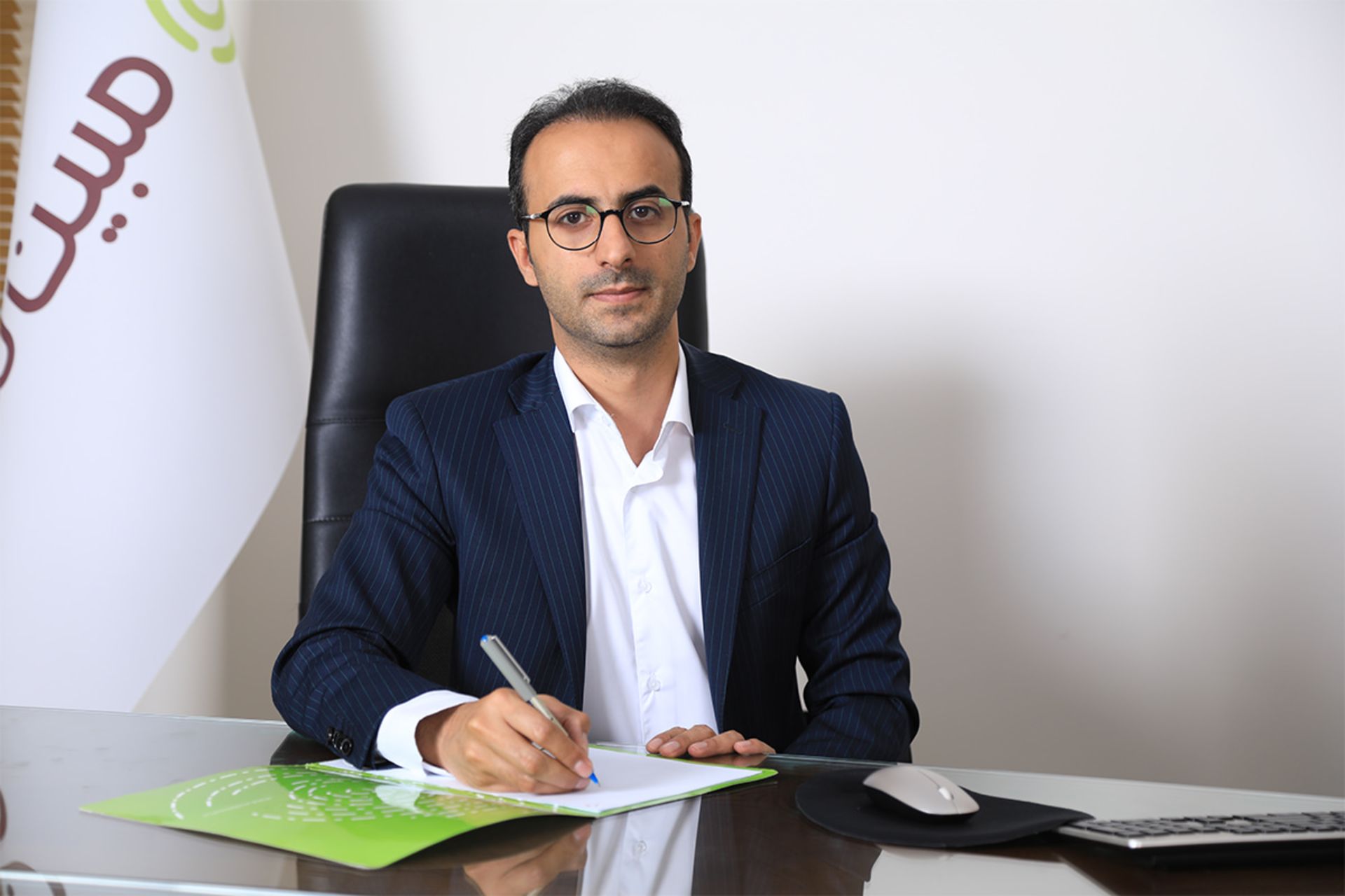 حسین طهرانی مدیرعامل مبین نت در دفتر با پرچم مبین نت