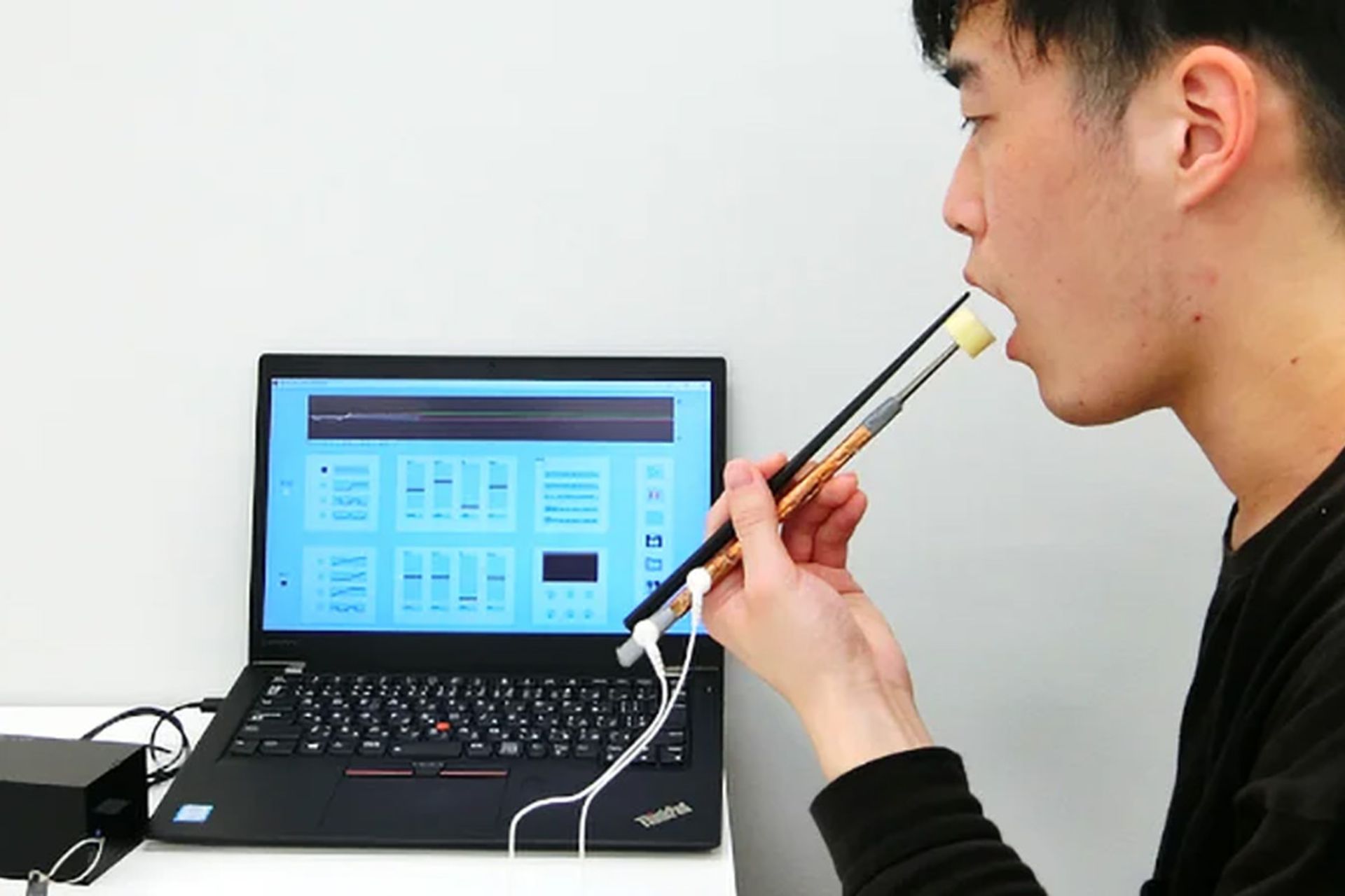 پسر ژاپنی در حال غذا خوردن با چاپستیک الکتریکی لپ تاپ