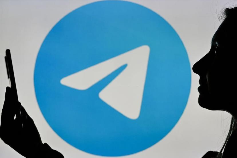 لوگو تلگرام / Telegram در پس زمینه یک زن با گوشی در دست