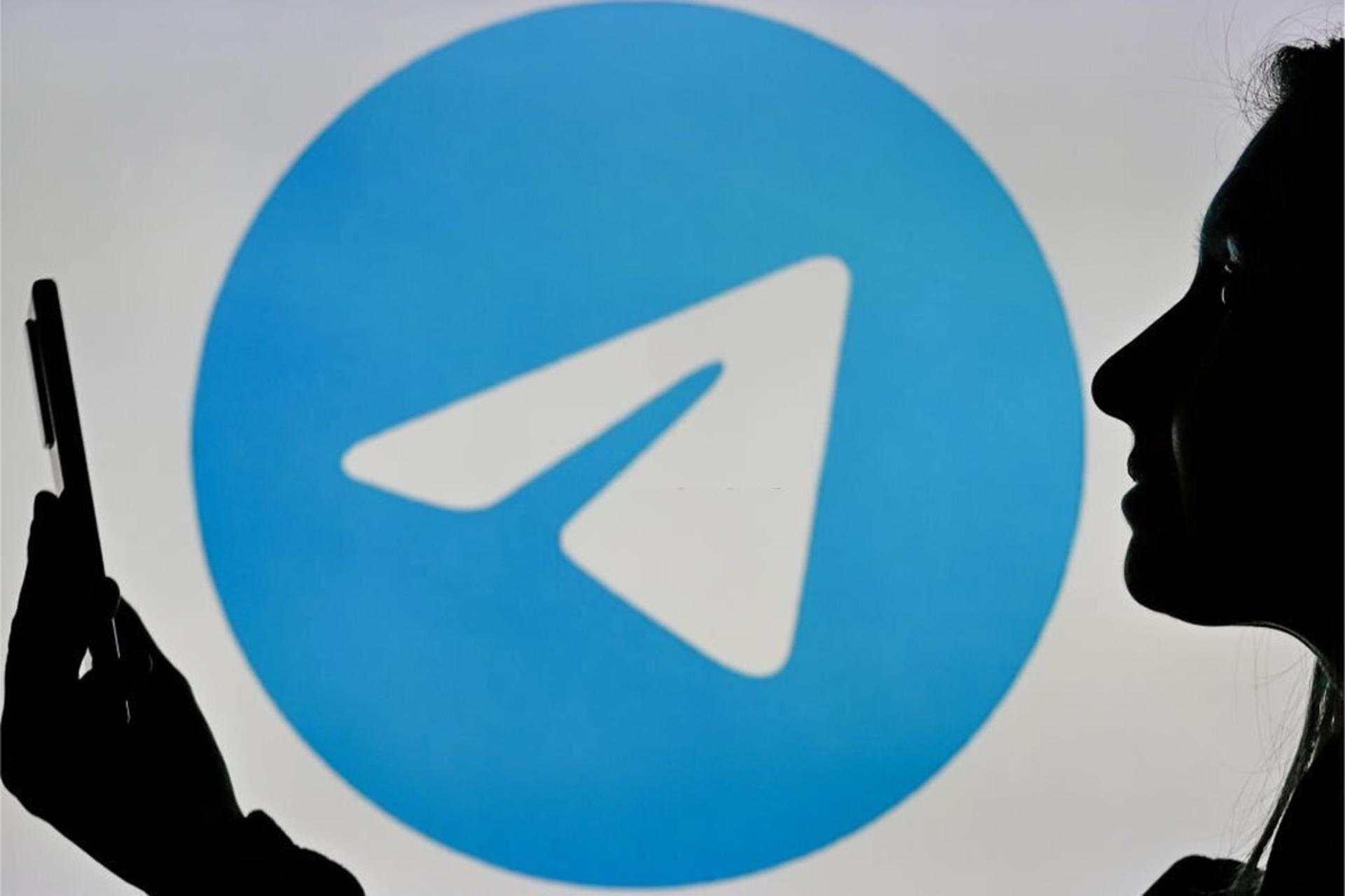 لوگو تلگرام / Telegram در پس زمینه یک زن با گوشی در دست