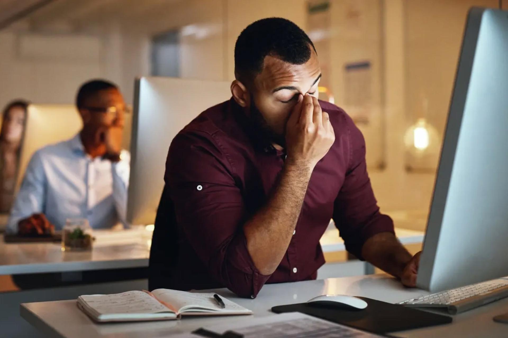 مرد خسته از نشستن بیش از حد لباس قرمز محیط کار