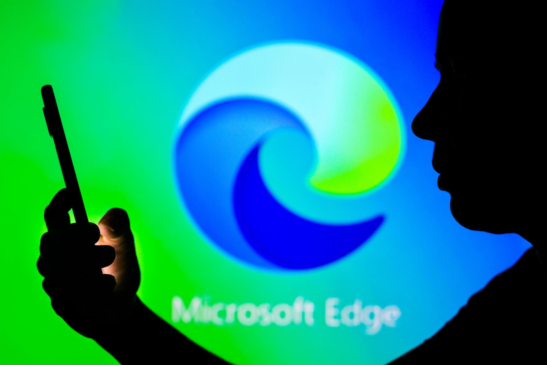 یک مرد در حال استفاده از گوشی لوگو مایکروسافت اج / Microsoft Edge در پس زمینه