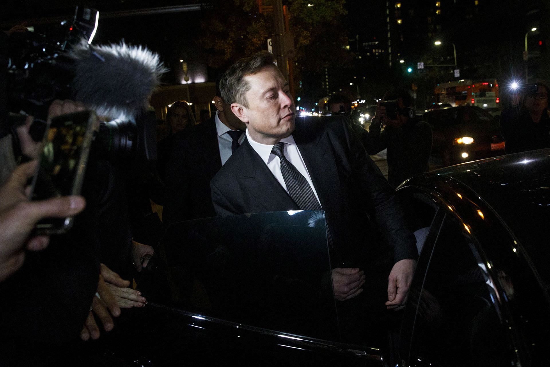 ایلان ماسک Elon Musk در حال ورود به خودرو در بین خبرنگاران شب