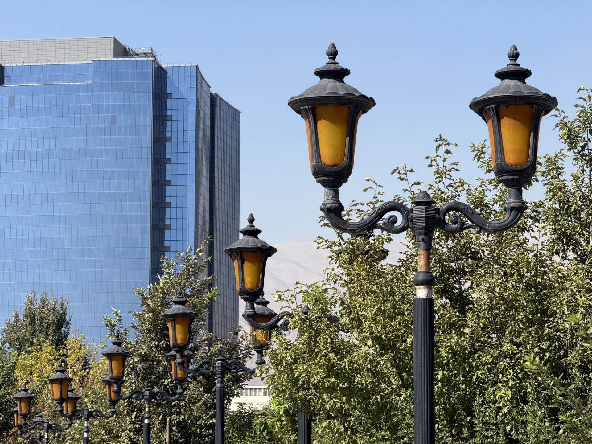 Street lights in front of a tall glass building - iPhone 16 Pro telephoto camera