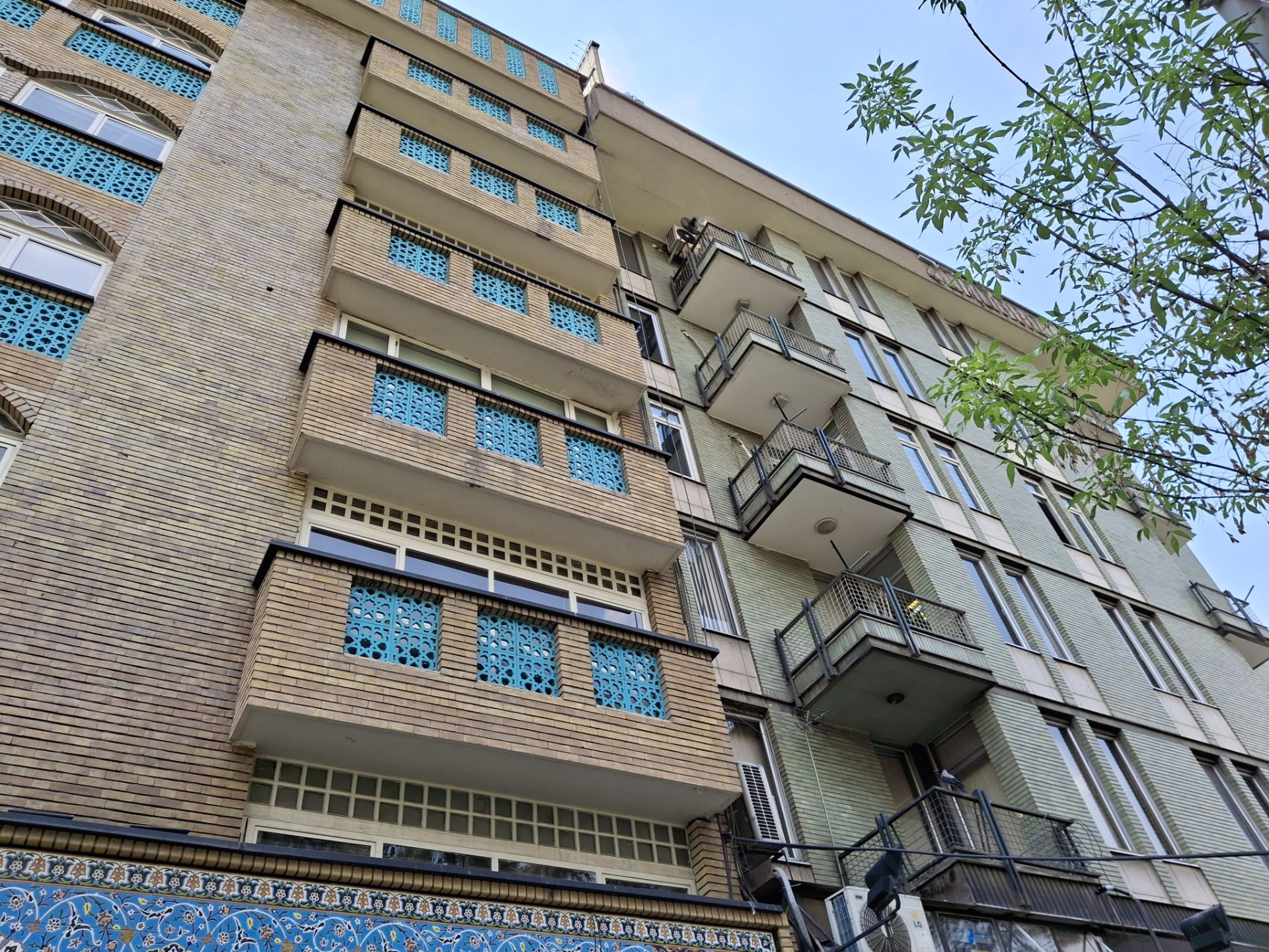 نمای پایین به بالای بیرونی یک ساختمان آجری در نور روز با دوربین گلکسی A35