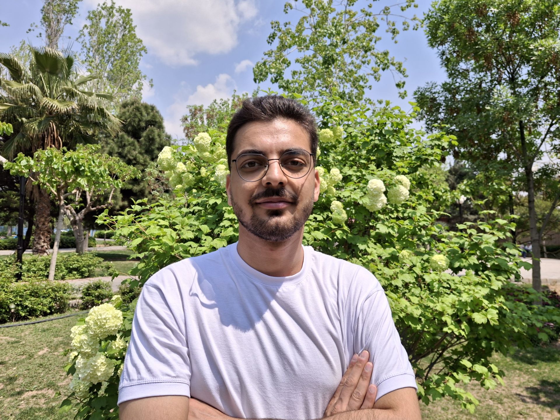 تصویر مرد جوان با تیشرت سفید در نور روز در یک پارک با دوربین گلکسی A35