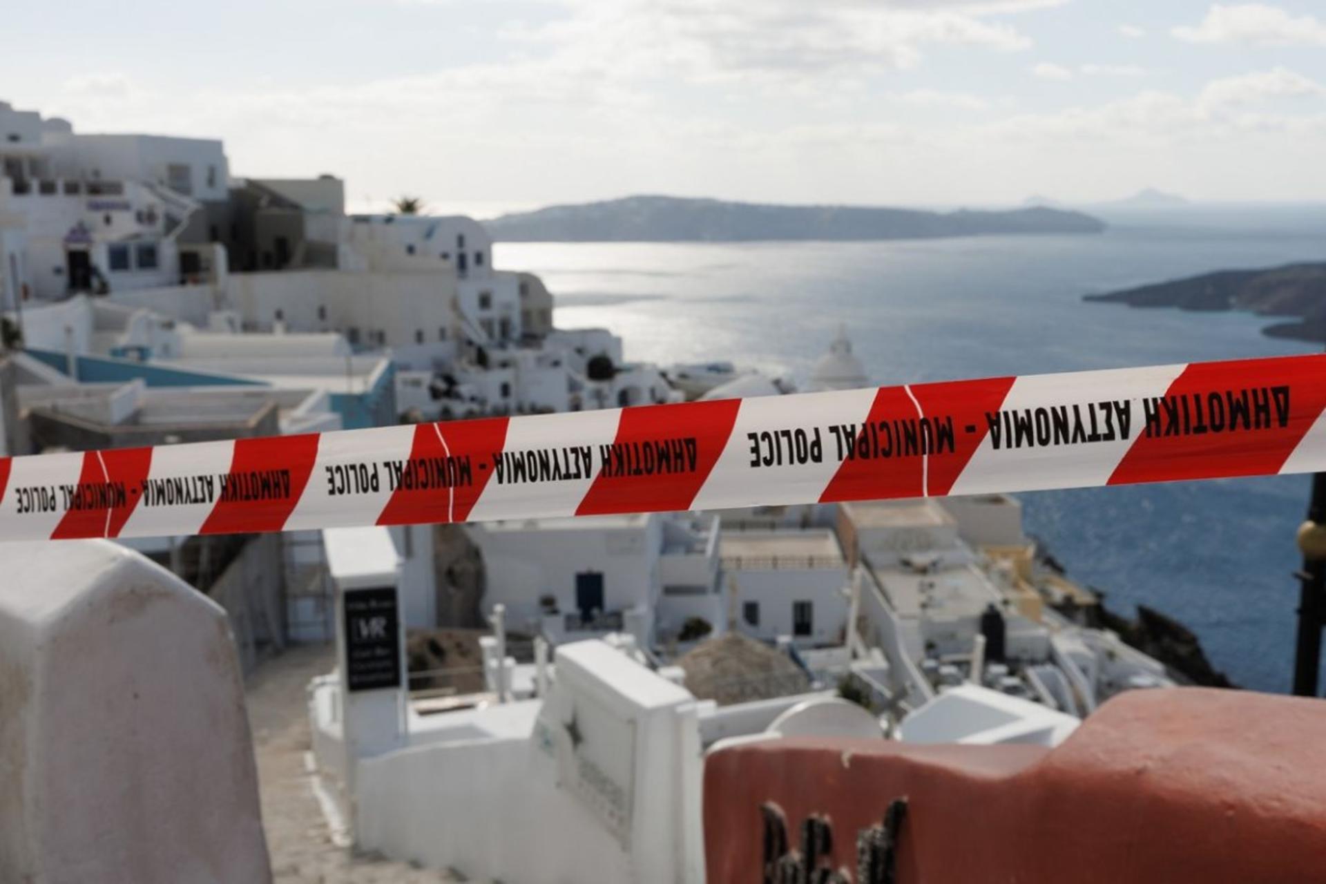 نوار قرمز و سفید پلیس شهرداری در مقابل چشم‌انداز خانه‌های سفید و آبی سانتورینی که رو به دریای اژه قرار دارند، در پی وقوع زمین‌لرزه‌های اخیر.