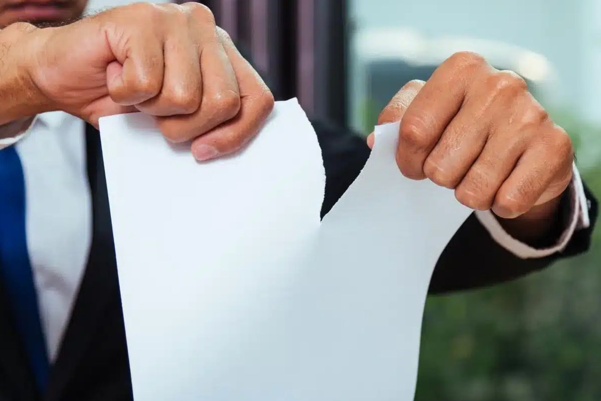 مرد جوان درحال پاره‌کردن یک ورق کاغذ است