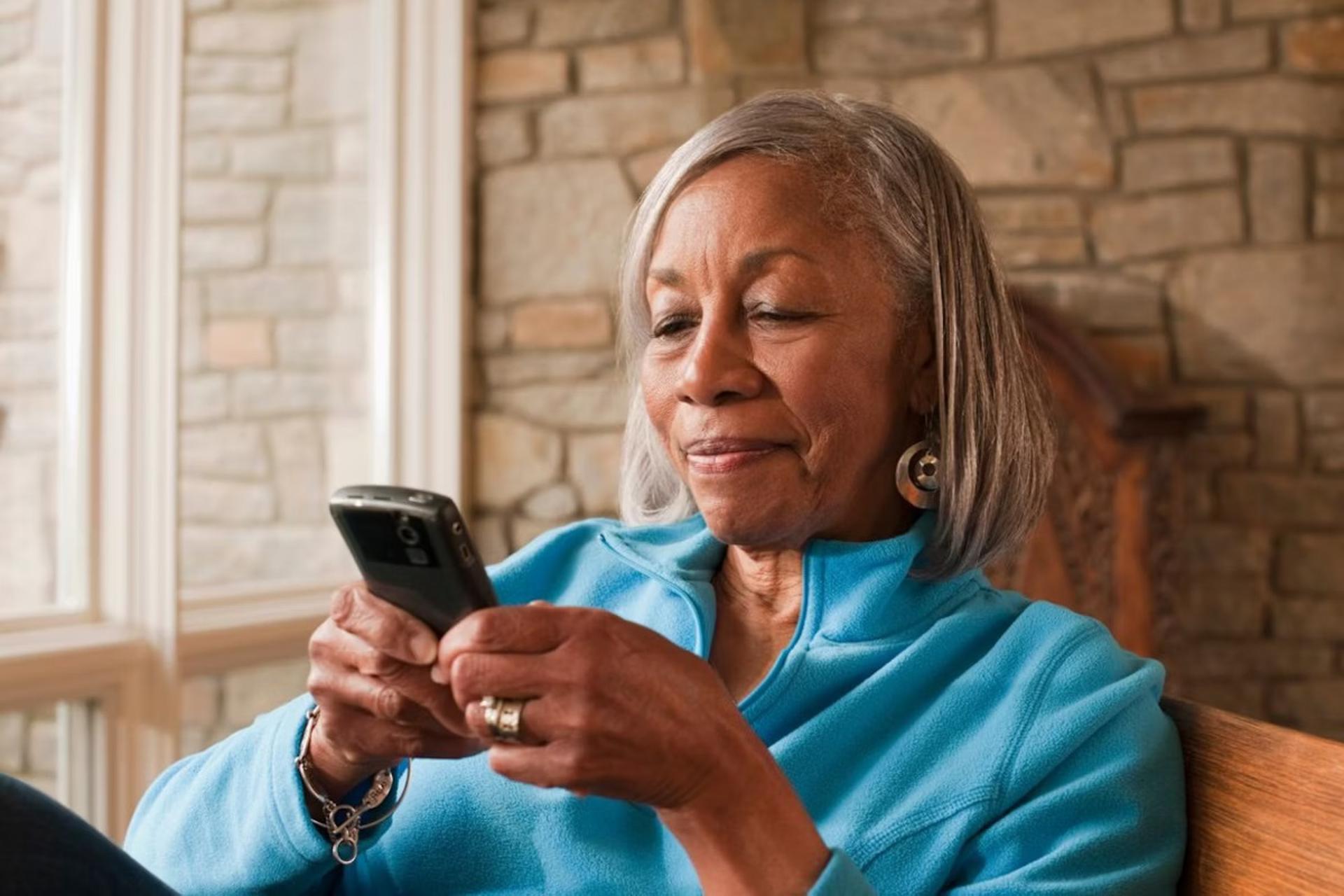 زن سالمند درحال کارکردن با گوشی هوشمند است