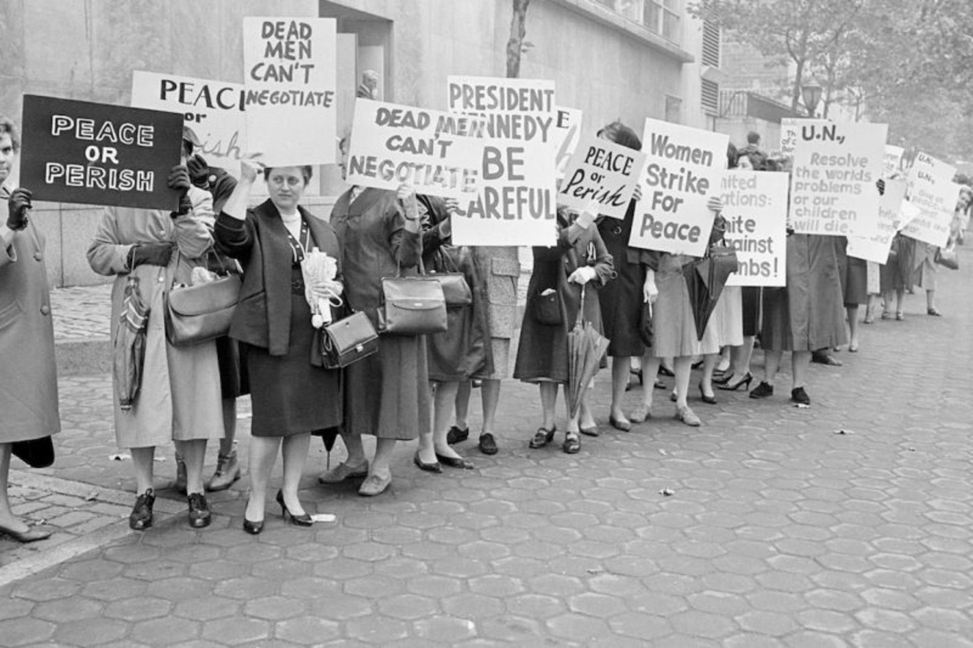 اعضای گروه «اعتصاب زنان برای صلح» با پلاکاردهایی در برابر مقر سازمان ملل متحد در شهر نیویورک، ۲۳ اکتبر ۱۹۶۲.