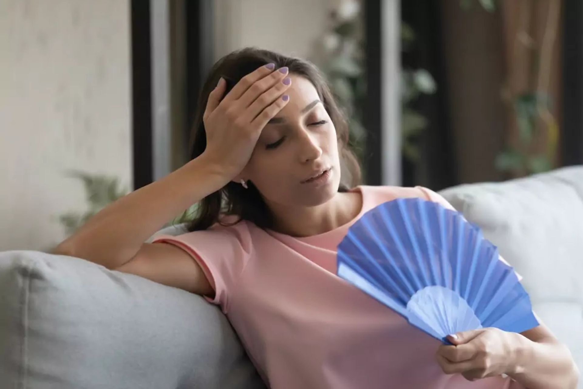 زن جوان درحال بادزدن خود با بادبزن است