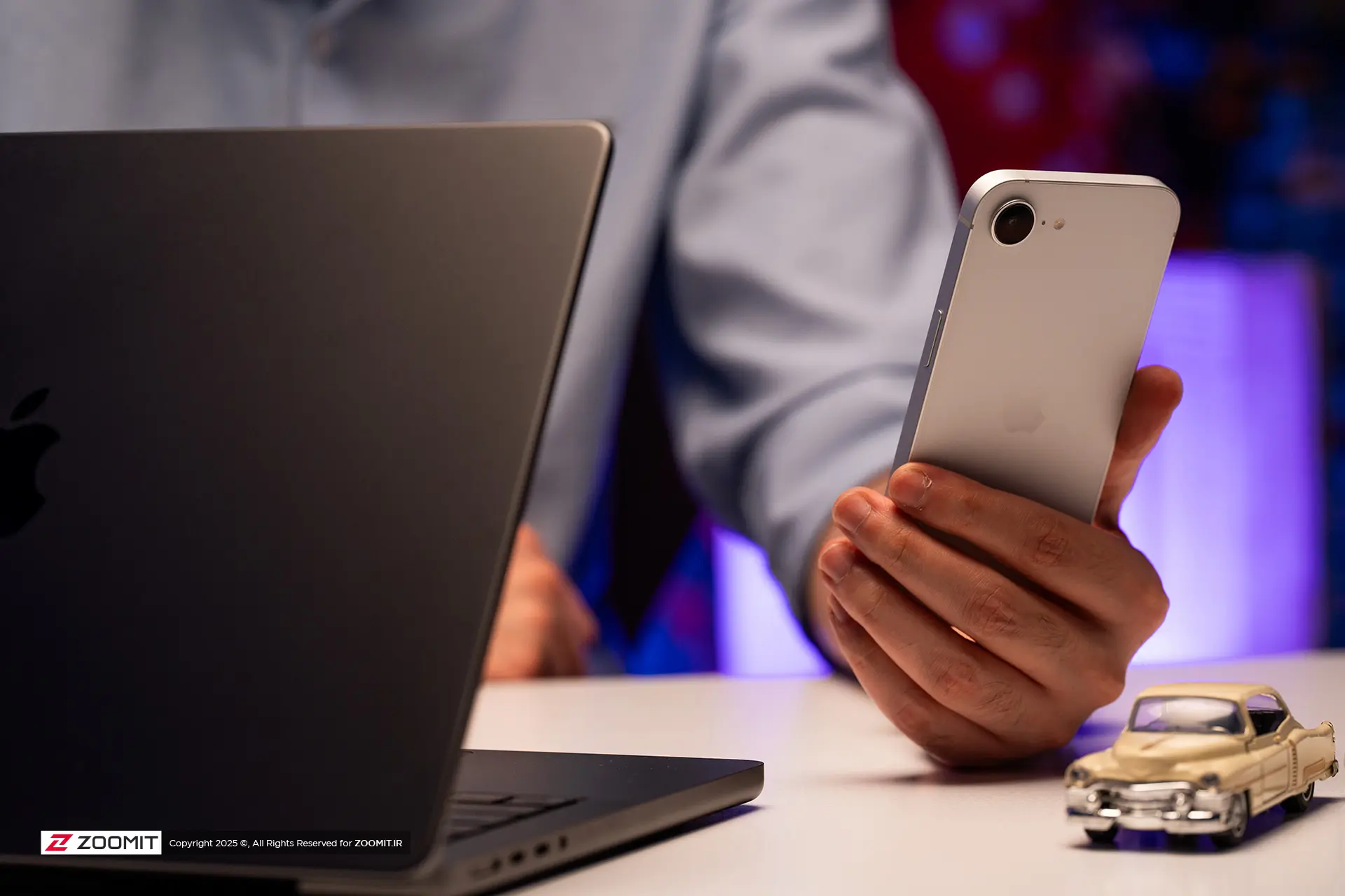 کاربری درحال کار با آیفون ۱۶ ای اپل در کنار مک بوک