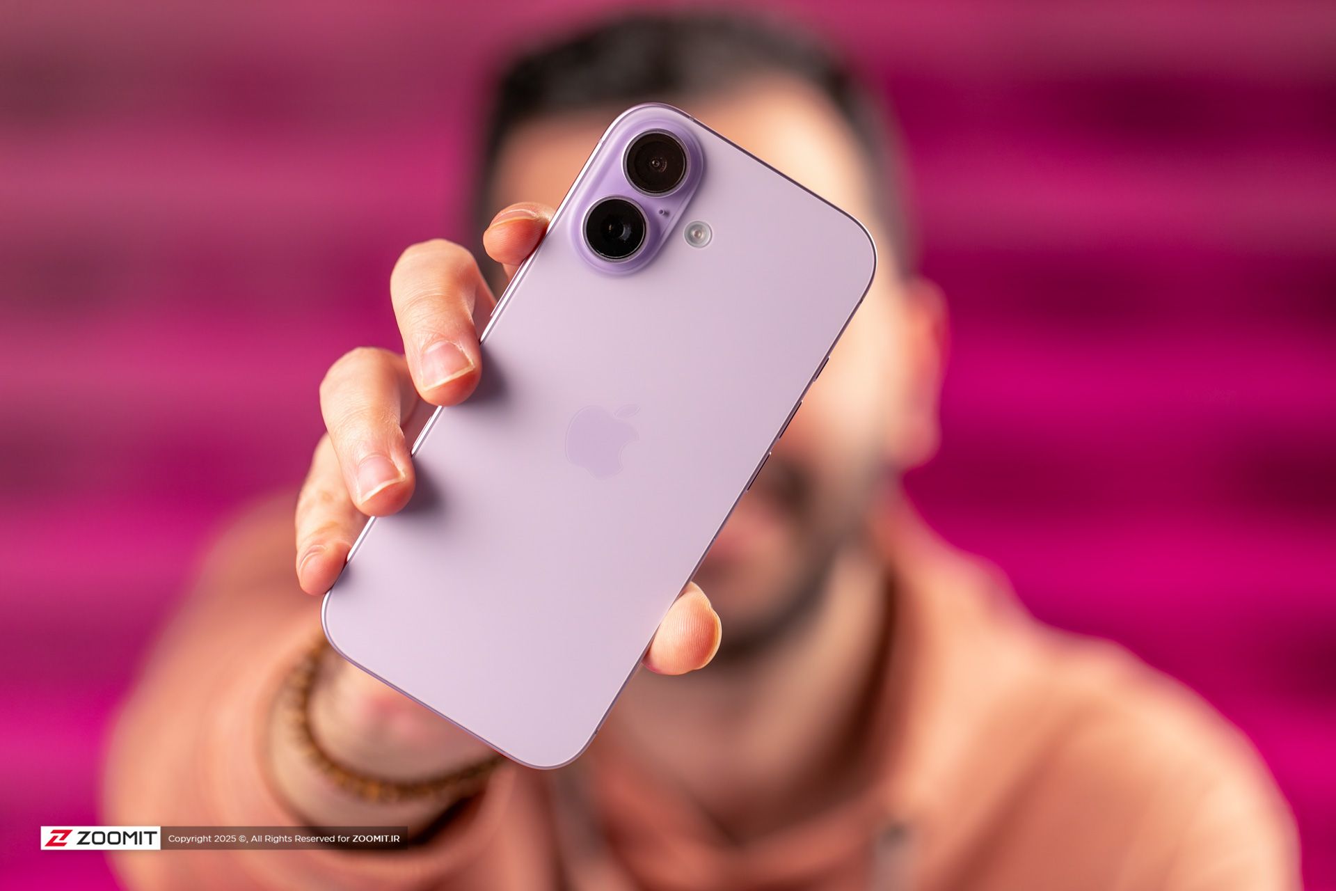 کاربر در حال نگه‌داشتن آیفون بنفش افقی جلوی صورت