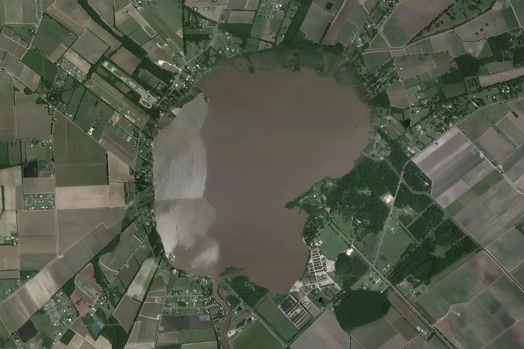 دریاچه بزرگ با رنگ قهوه‌ای در میان زمین‌های کشاورزی