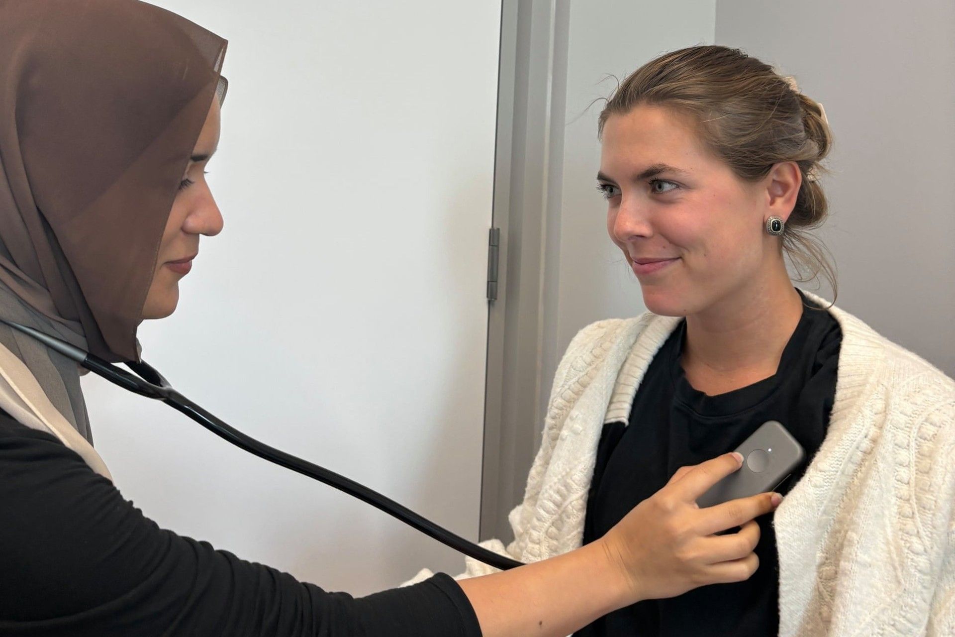 یک پزشک در حال معاینه‌ی زن جوان با گوشی پزشکی