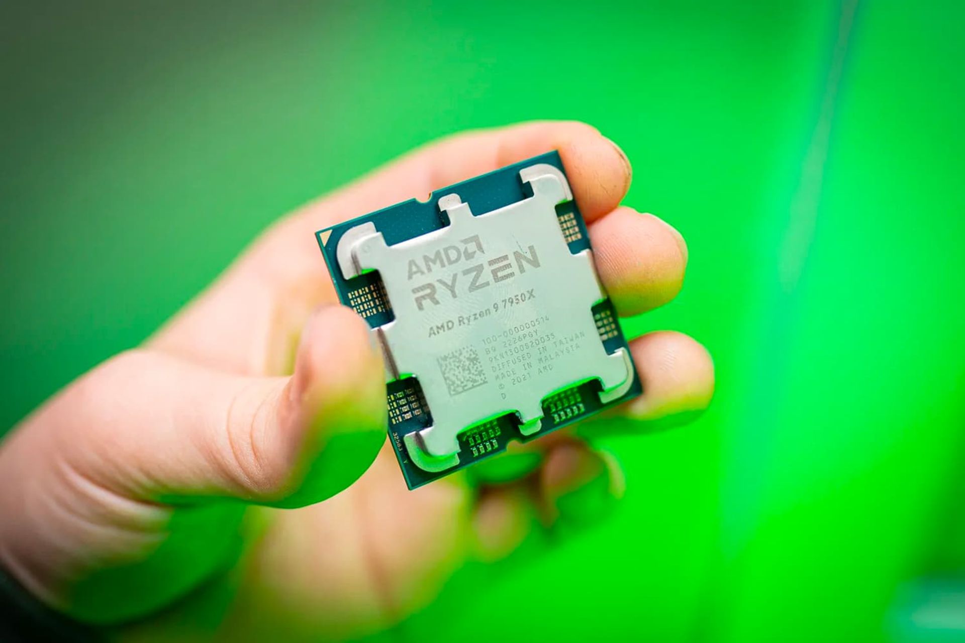 پردازنده AMD 7950X در دست پس زمینه سبز