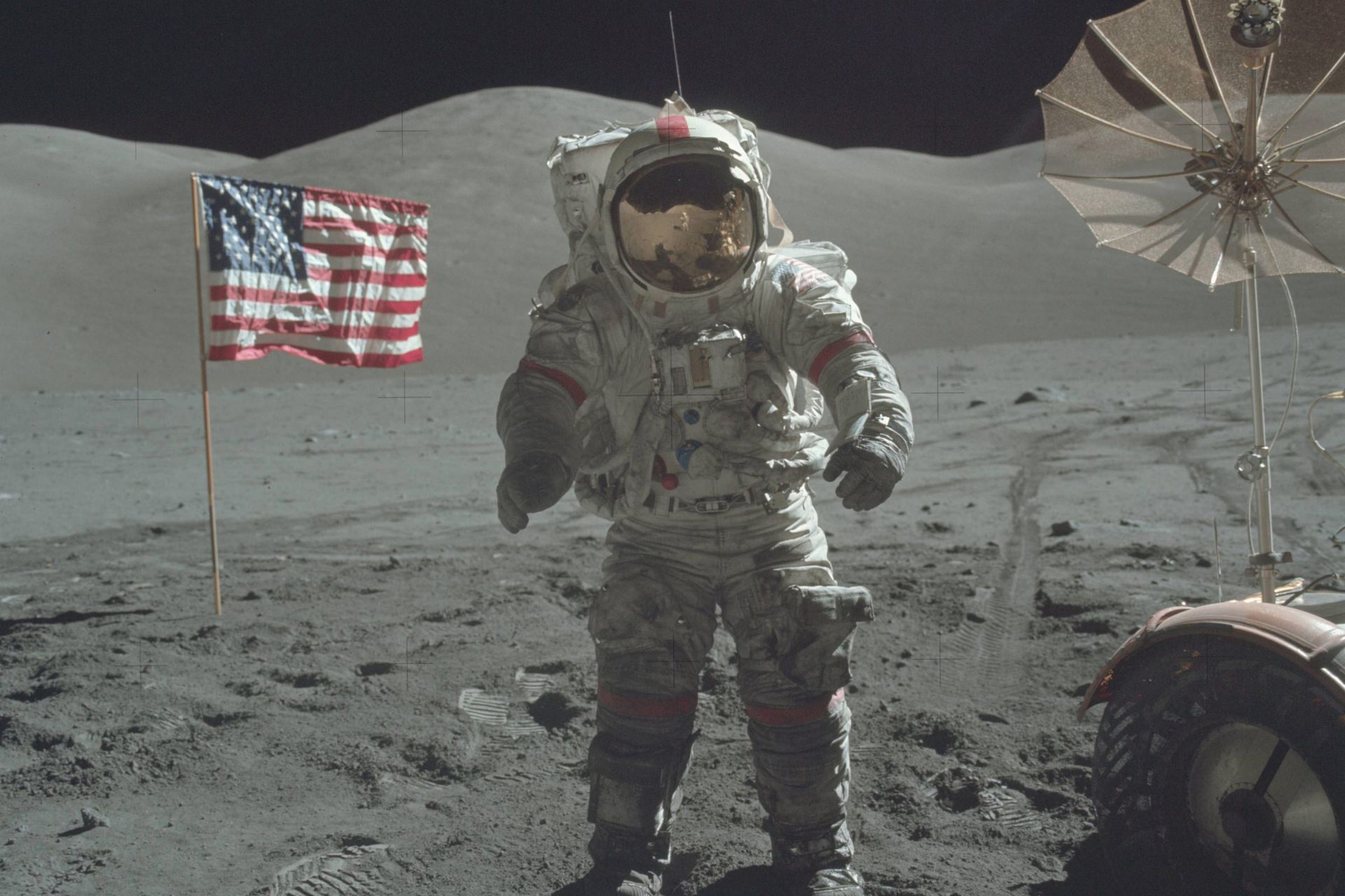 فضانورد آپولو ۱۷ ایستاده روی سطح ماه در کنار ماه‌نورد و پرچم آمریکا