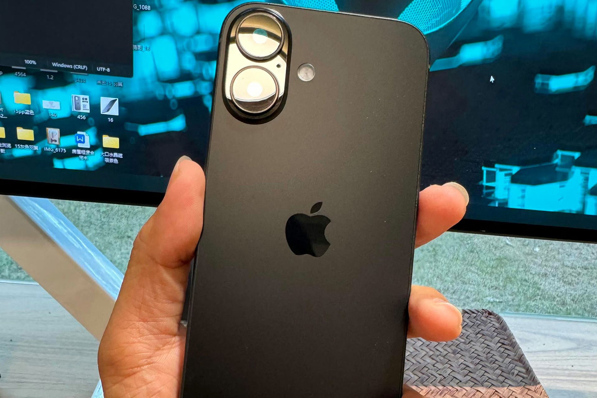 Showing the back panel of the iPhone 16 in the hand of a user