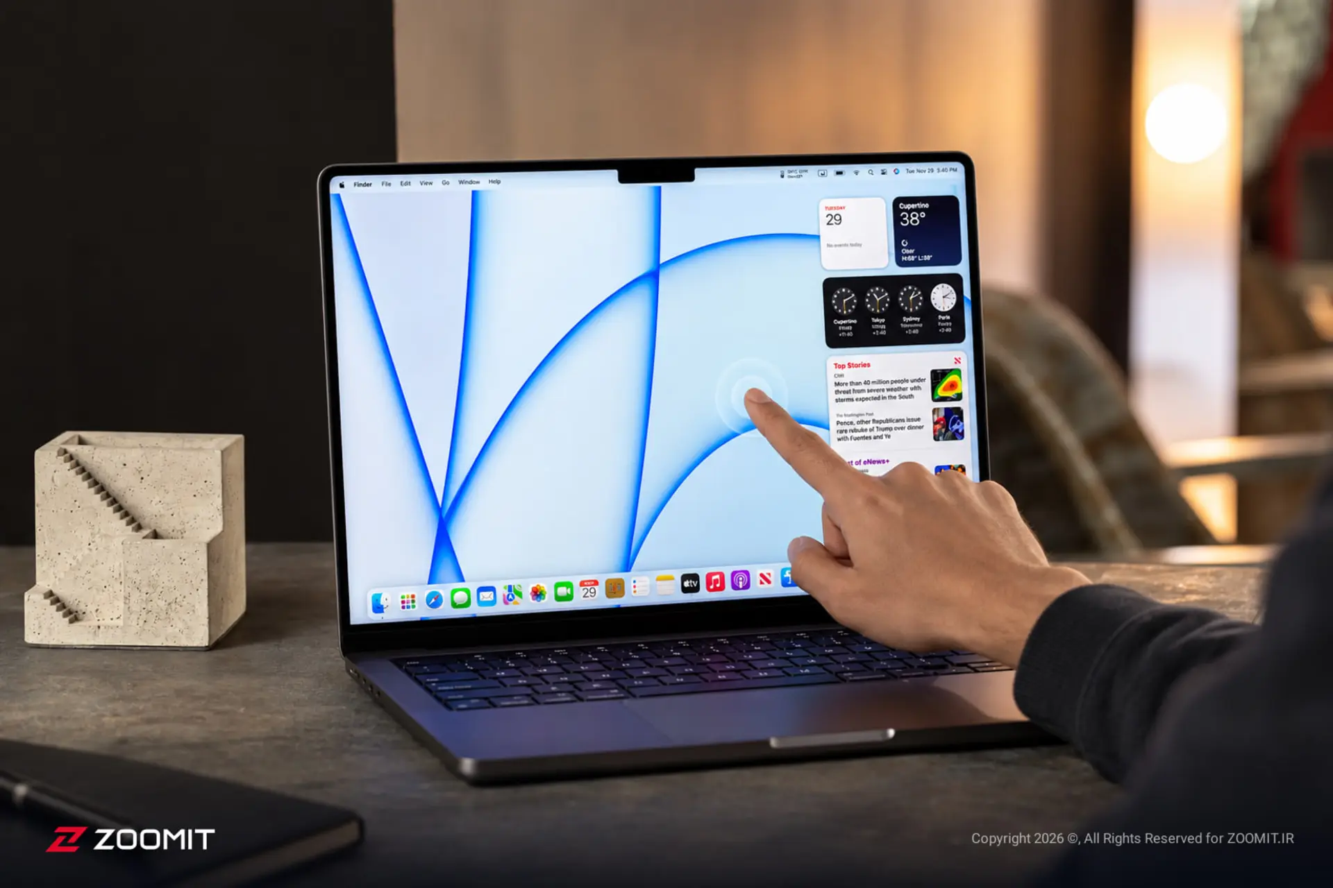 نمای نزدیک از دست کاربر در حال لمس صفحه نمایش لپ‌تاپ اپل (Apple)