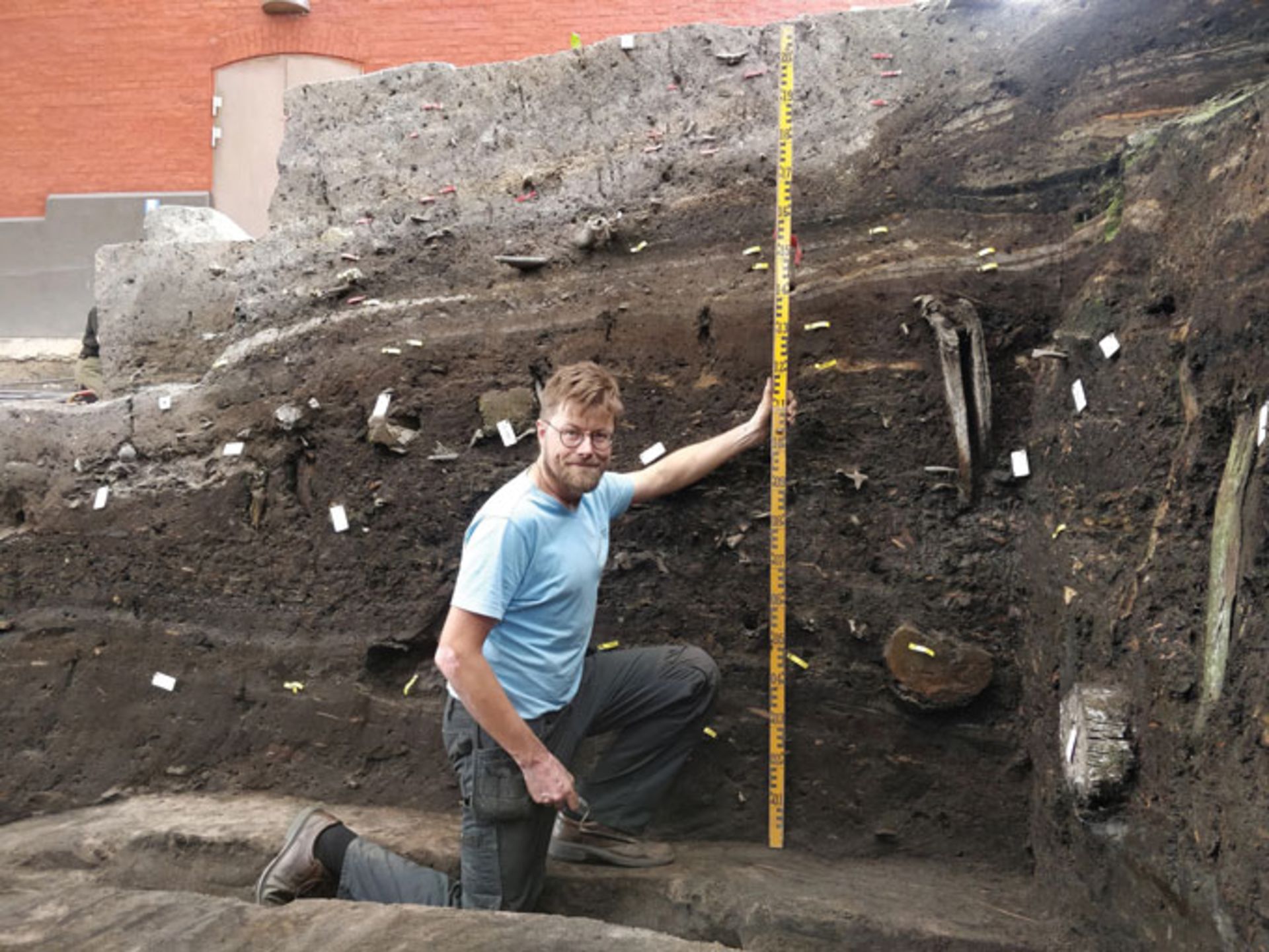 باستان‌شناس سورن سیندبک در یک گودال حفاری زانو زده است و لایه‌های باستان‌شناسی ریبه را بررسی می‌کند.