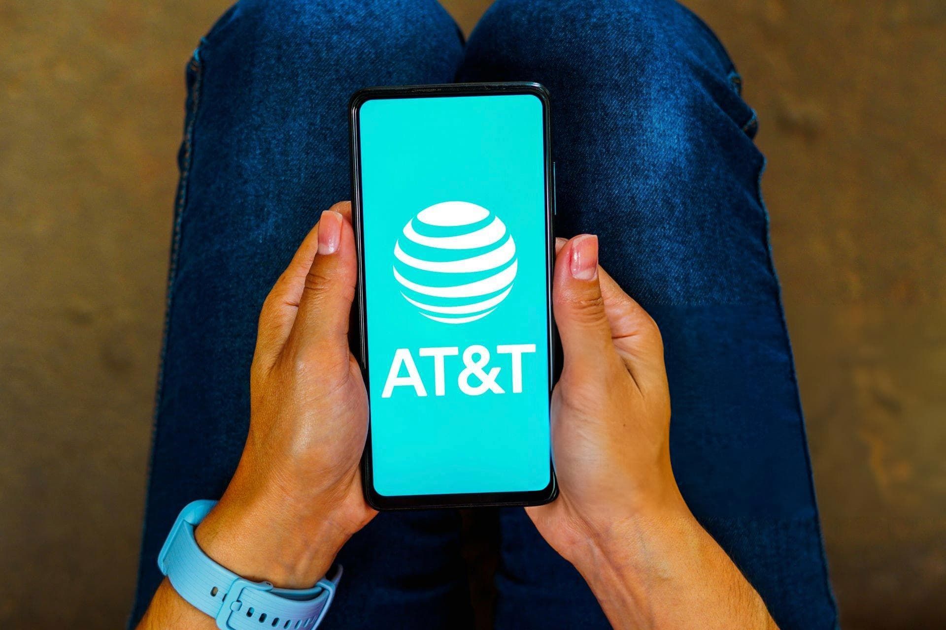 لوگو AT&T روی نمایشگر موبایل در دست یک دختر