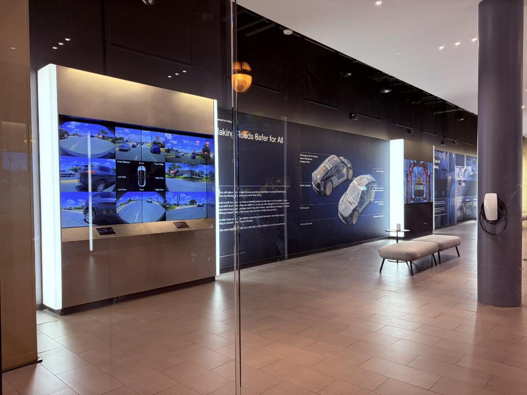 نمایشگر بزرگ دیجیتال در یک نمایشگاه خودرو که ویژگی‌های سیستم رانندگی خودکار را نشان می‌دهد.