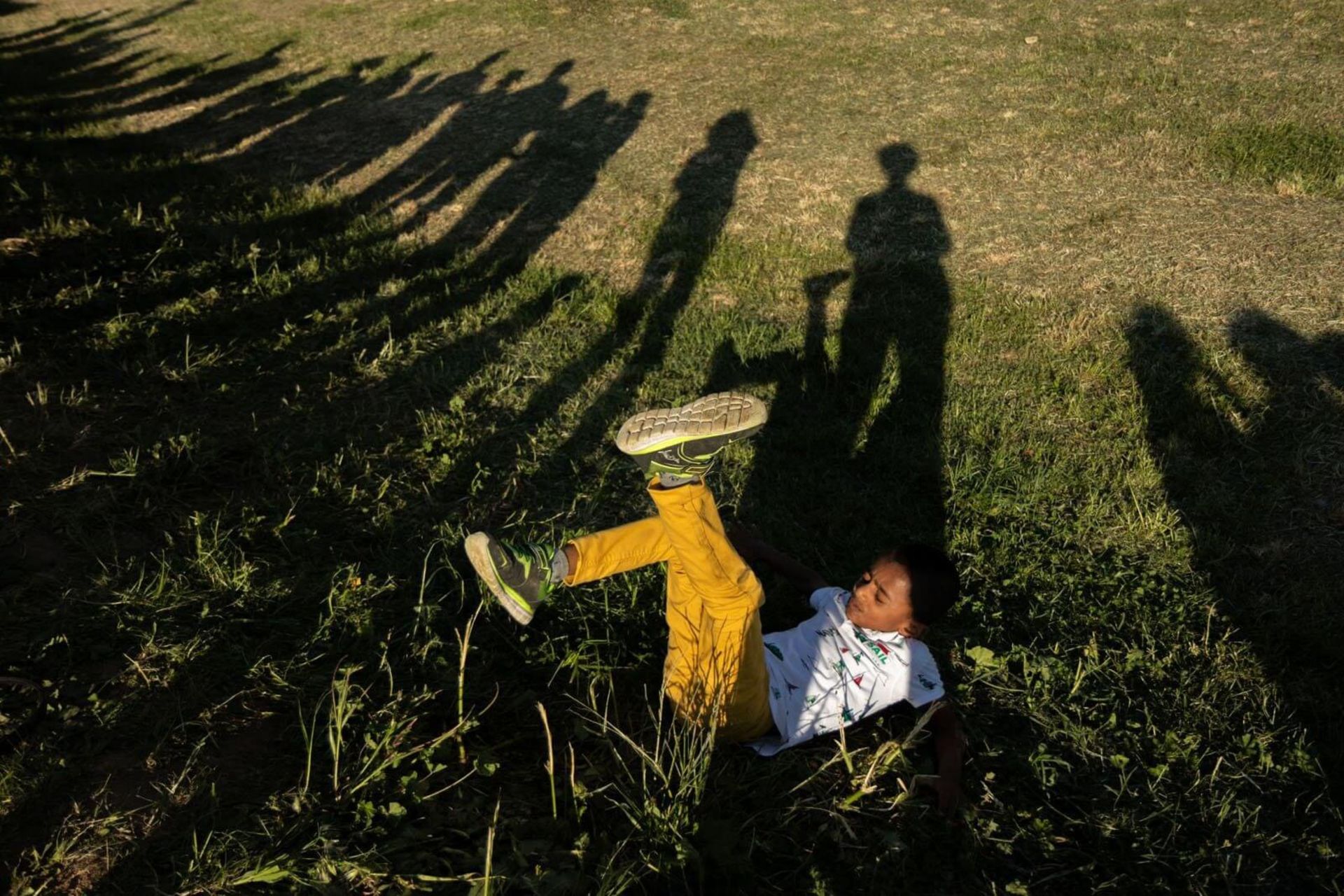 پسر بچه روی زمین با لنگ های در هوا