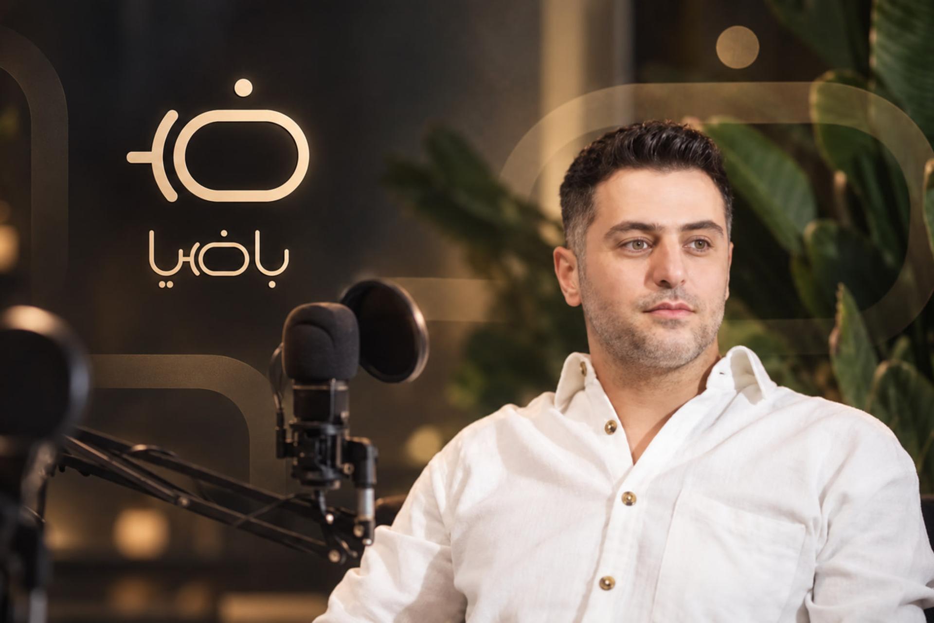 علی ضیا در مقابل میکروفون در استودیوی پادکست