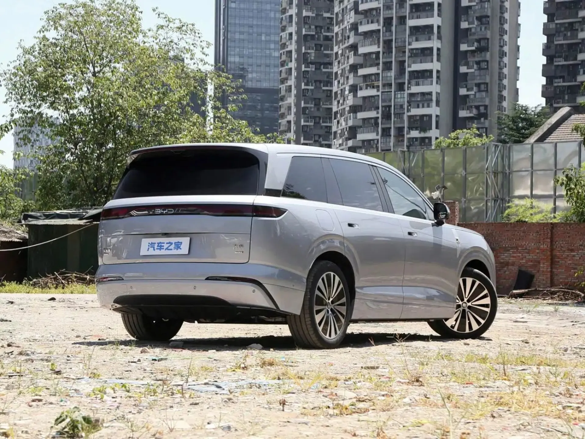 یک دستگاه خودروی برقی بایک مدل SUV در کنار ساختمانی بلند و محوطه‌ای با کف سنگفرش شده