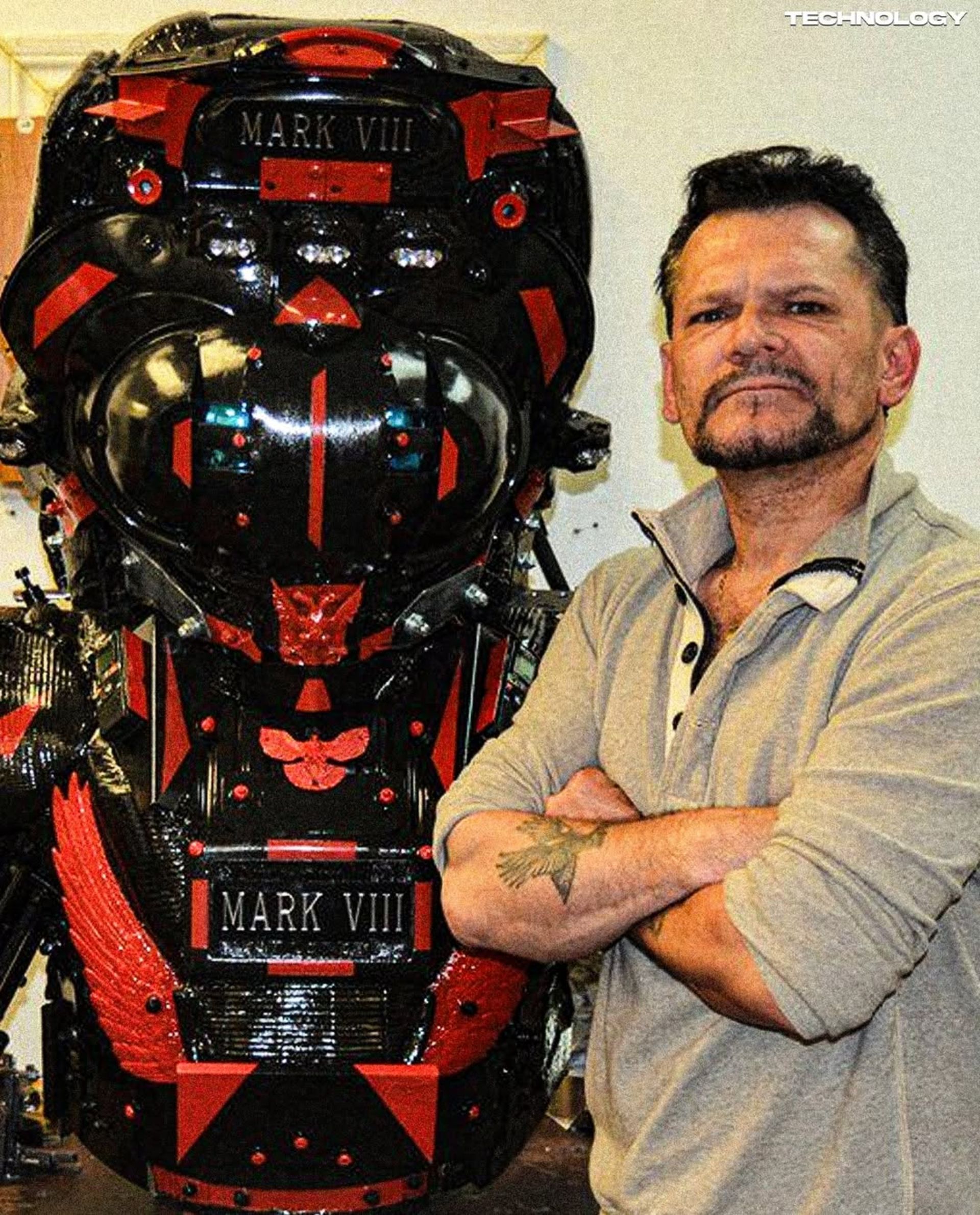 یک مرد کنار لباس فلزی و بزرگ به رنگ قرمز