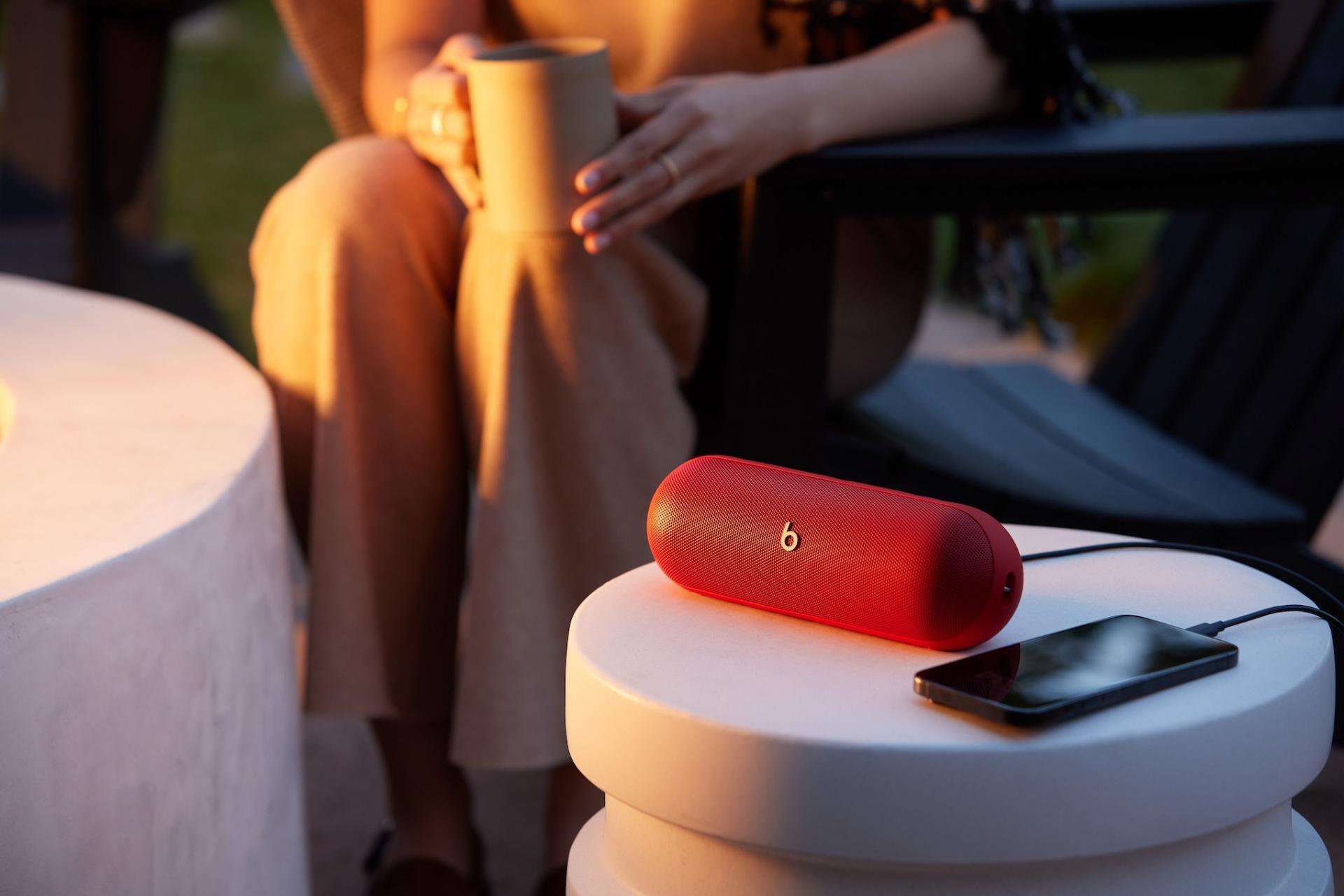 اسپیکر Beats Pill مدل ۲۰۲۴ روی میز درحال شارژ آیفون