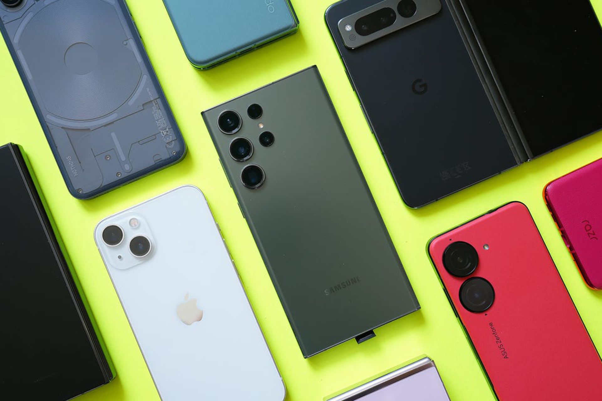 چند گوشی هوشمند از برندهایی مثل سامسونگ و اپل و ایسوس از نمای پشت روی میز