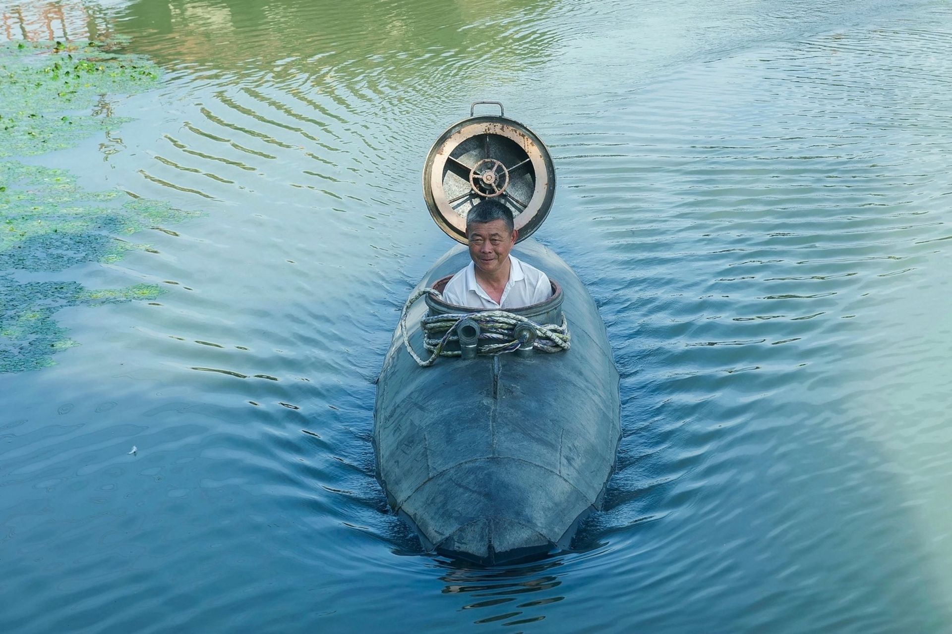 یک پیرمرد سوار بر یک زیردریایی روی سطح آب