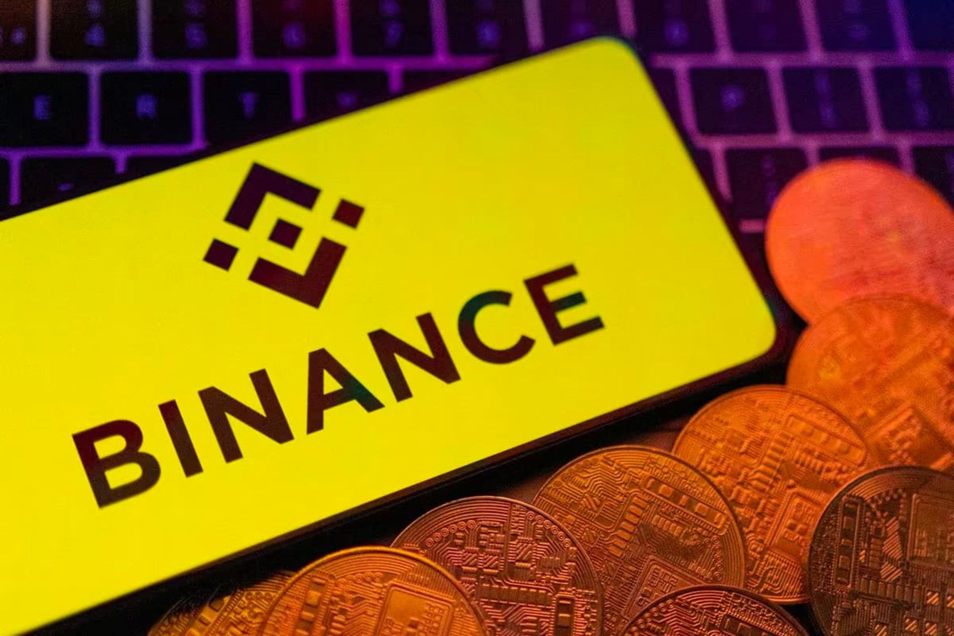 لوگو بایننس / Binance روی نمایشگر گوشی در کنار سکه زرد