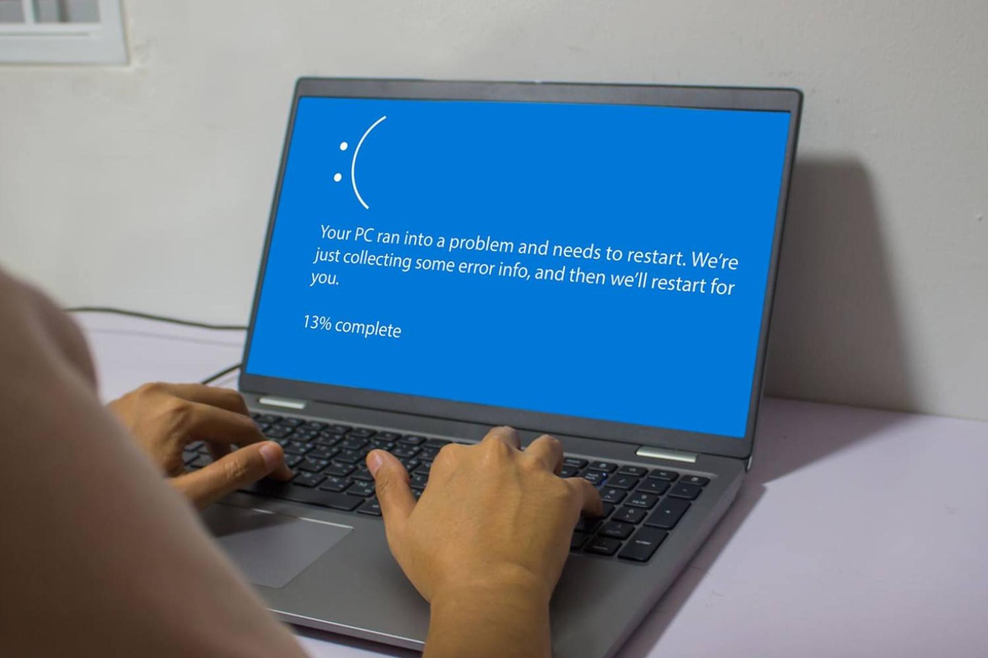 کاربر درحال کار با کامپیوتری که صفحه آبی مرگ ویندوز را نمایش می دهد