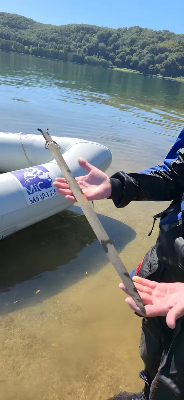 شمشیر قدیمی عصر برنز در دستان یک کاوشگر در کنار دریاچه