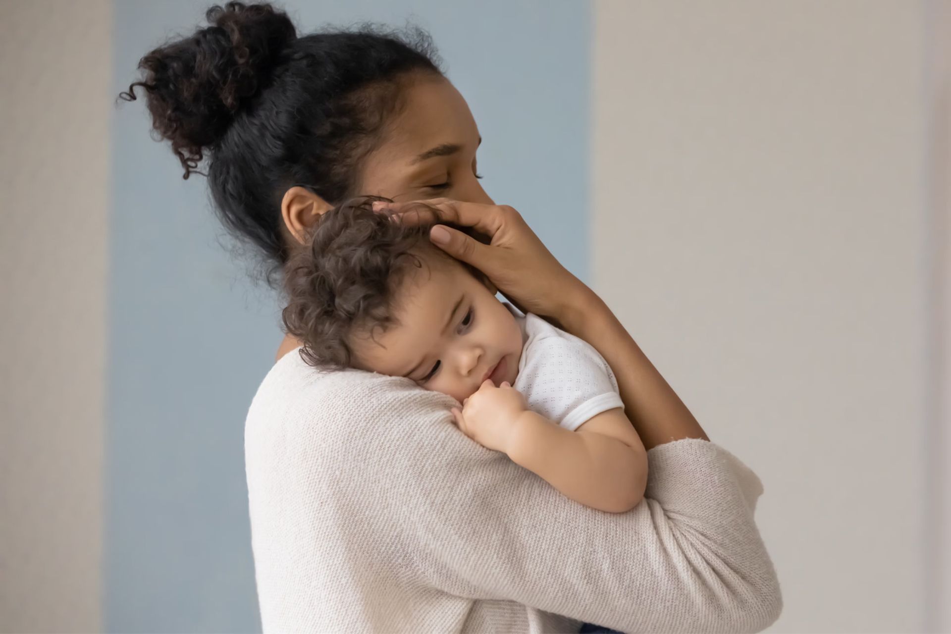 مادر جوانی پسربچه‌ی نوزاد خود را در آغوش گرفته