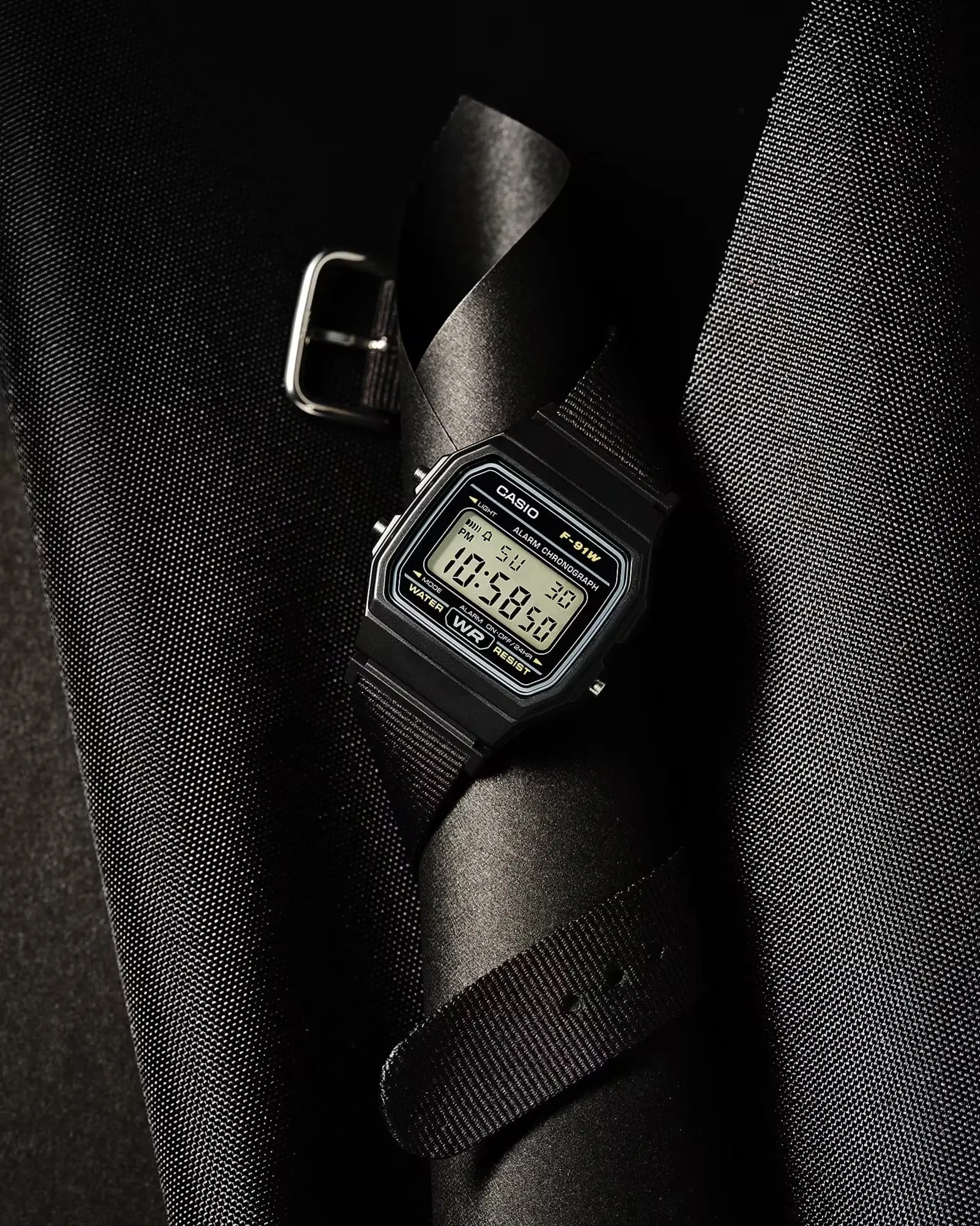 ساعت دیجیتال کاسیو (Casio F-91WF) با بند مشکی روی پس‌زمینه تیره