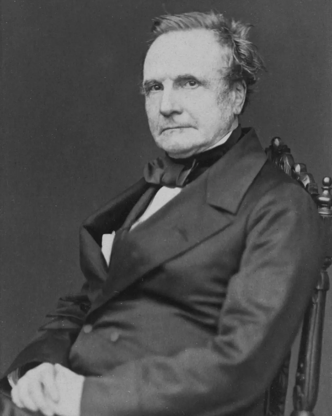 چارلز ببیج (Charles Babbage) با لباس رسمی قرن نوزدهم در حالت نشسته