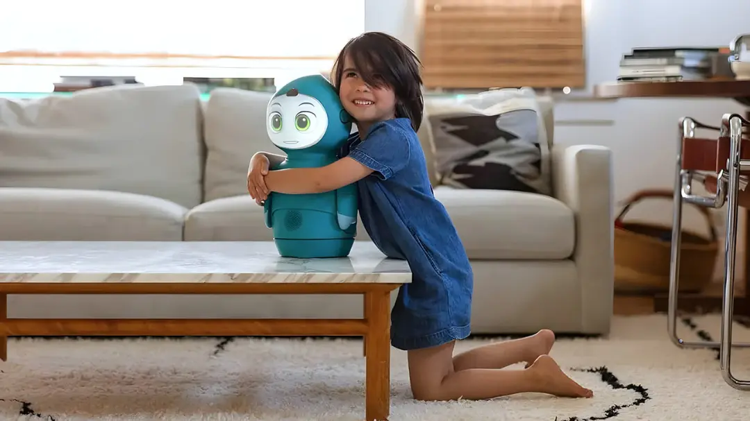کودک در حال در آغوش گرفتن ربات کوچک هوشمند (Smart Robot) روی میز