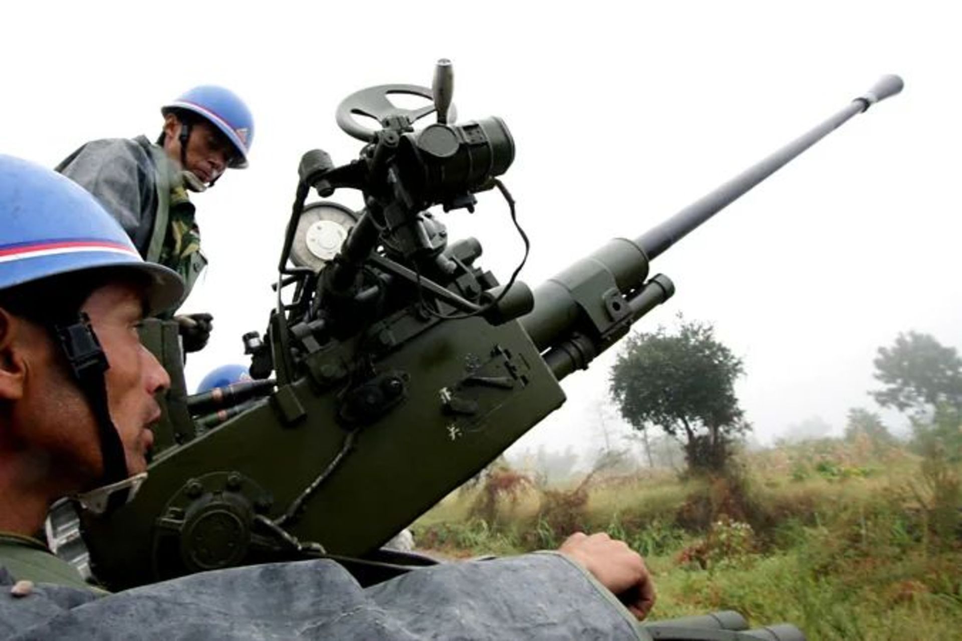 دو نظامی چینی در دو طرف یک موشک‌انداز ایستاده‌اند و یکی از آنها در حال بارگیری موشک است.