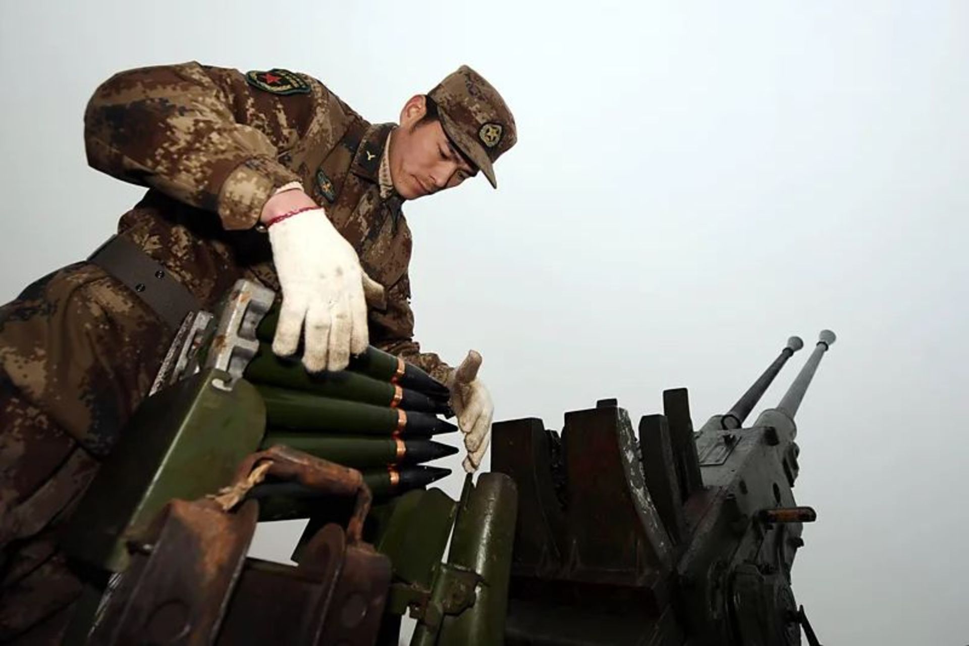 مرد نظامی چینی در کنار موشک‌انداز ایستاده و در حال بارگیری موشک است.