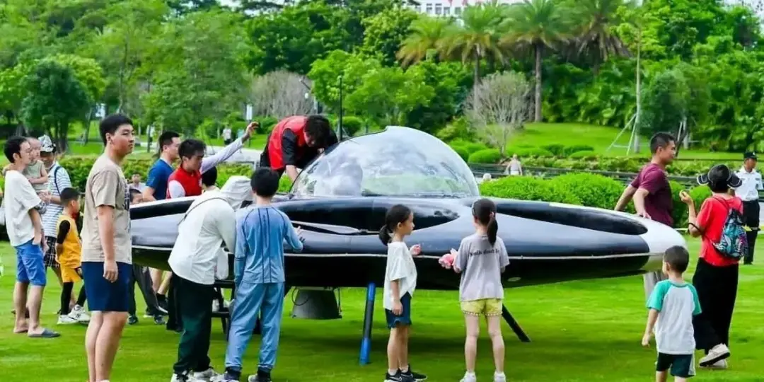 بشقاب‌پرنده سرنشین‌دار (Passenger Flying Saucer) در یک فضای سبز باز با حضور مردم