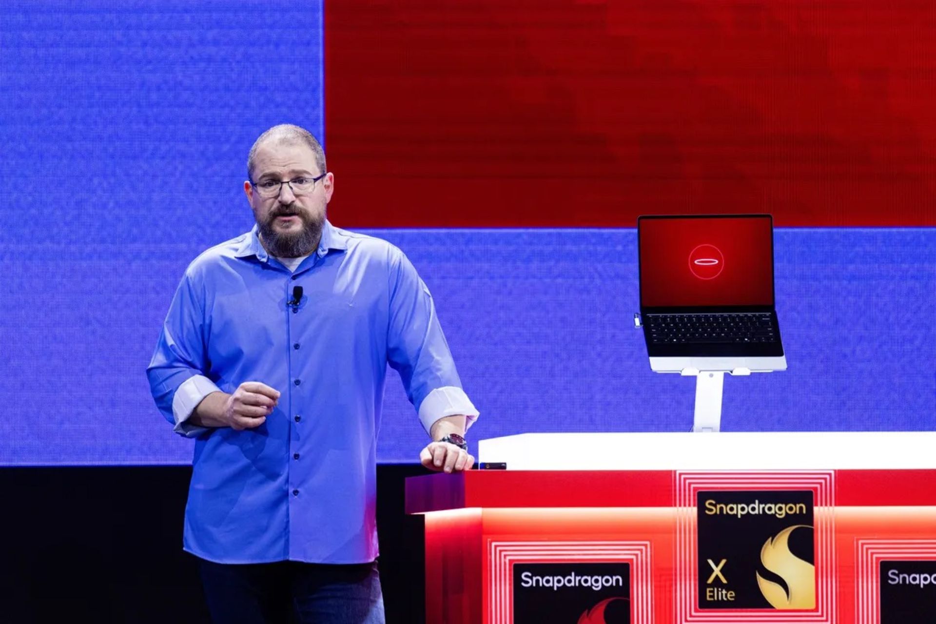 یک مرد میان‌سال با پیراهن آبی در حال نمایش تراشه‌های اسنپدراگون