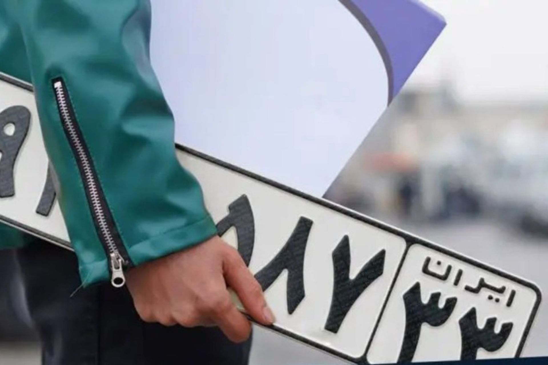 پلاک خودرو در دست یک شخص از نمای نزدیک