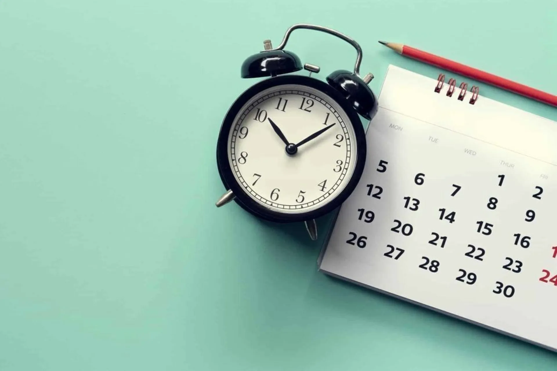 ساعت رومیزی در کنار تقویم کاغذی