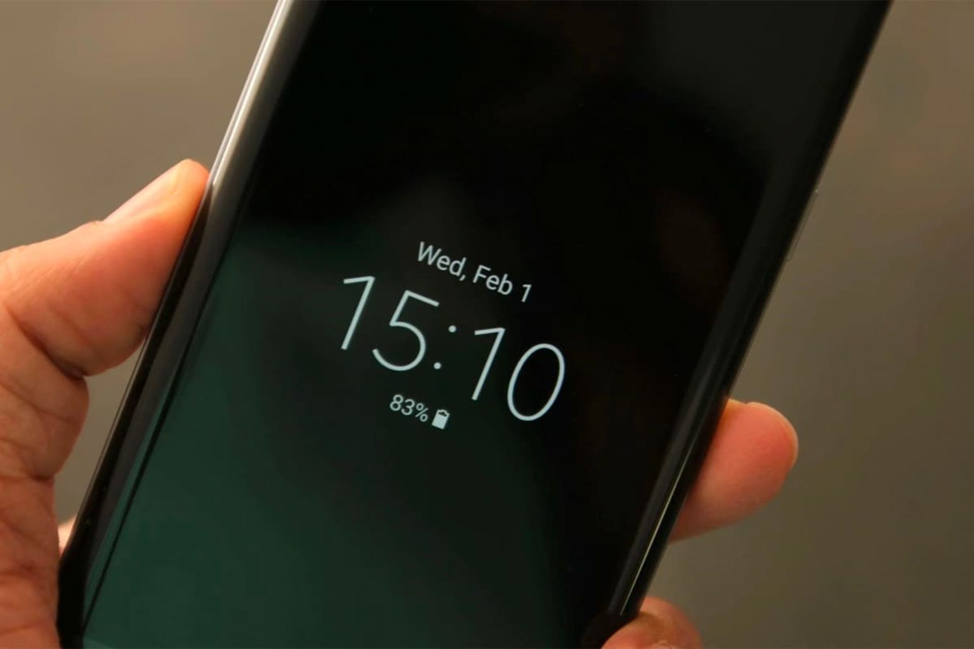 ساعت روی نمایشگر گوشی در دست