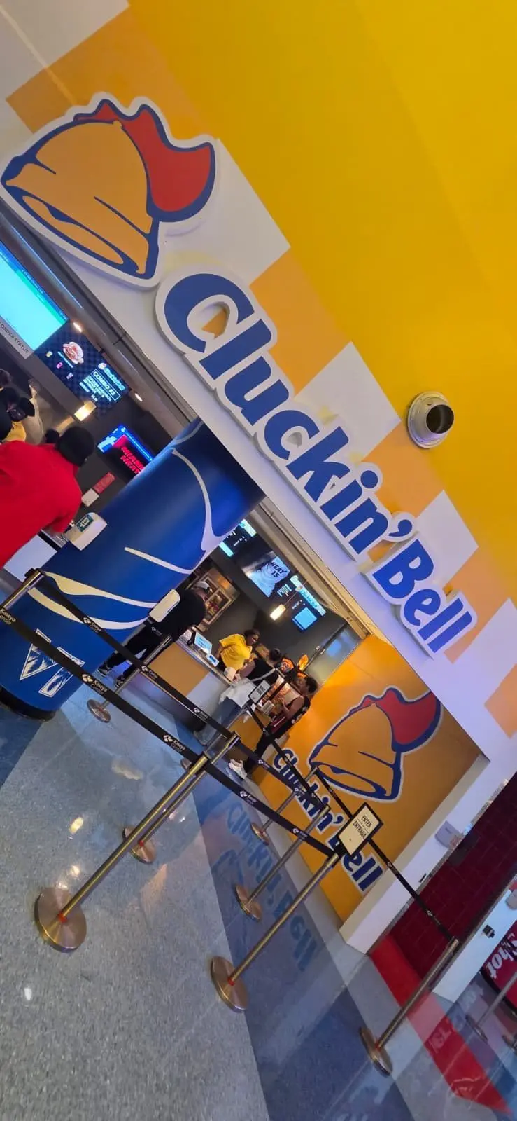 نمای داخلی شعبه رستوران کلکین بل (Cluckin' Bell) با لوگوی بزرگ زرد و آبی